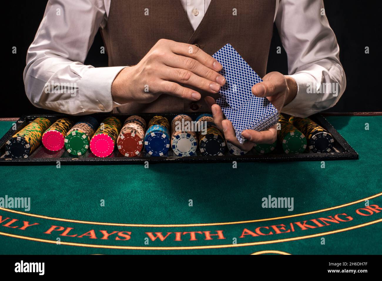 Nahaufnahme von holdem Dealer mit Spielkarten und Chips auf grünen Tisch Stockfoto