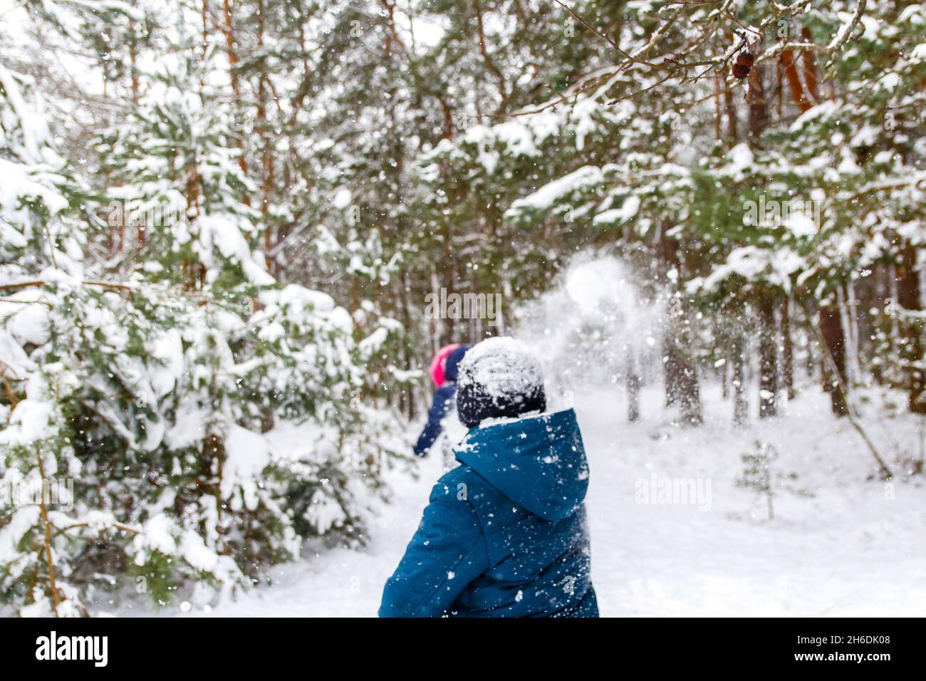 Der Junge wirft einen Schneeball auf das Mädchen. Lustige Kinder im Winter Park spielen Schneebälle und verbringen aktiv Zeit im Freien. Winter verschneiten Wald. Kalt f Stockfoto