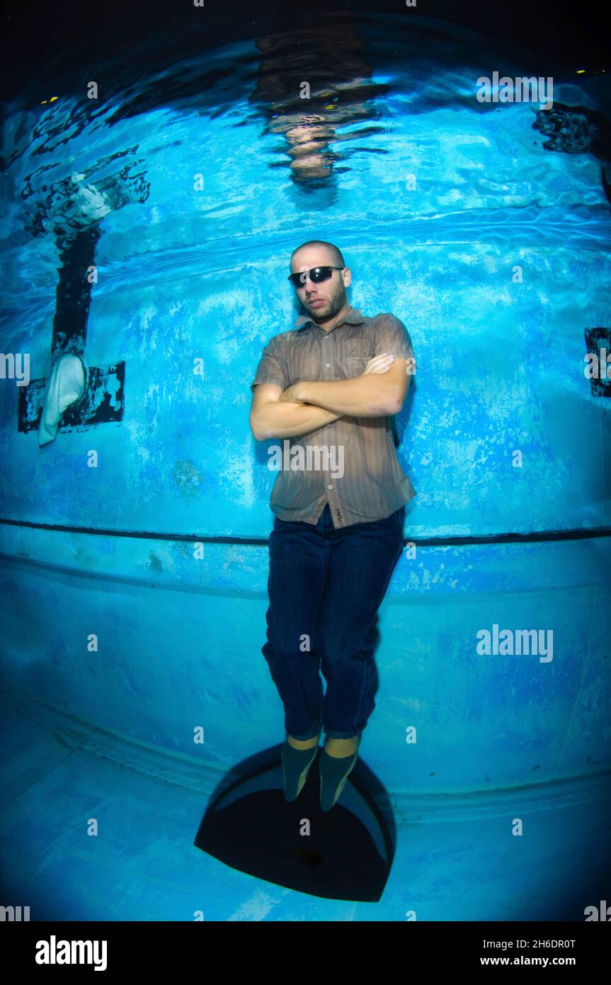 Mann in legerer Kleidung und Flossen, der in einem Pool freitauchte Stockfoto