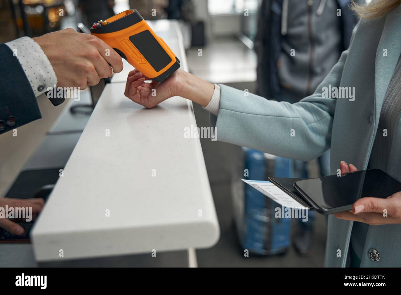 Flughafenmitarbeiter messen die Temperatur der Passagiere mit einem berührungslosen digitalen Handheld-Gerät Stockfoto
