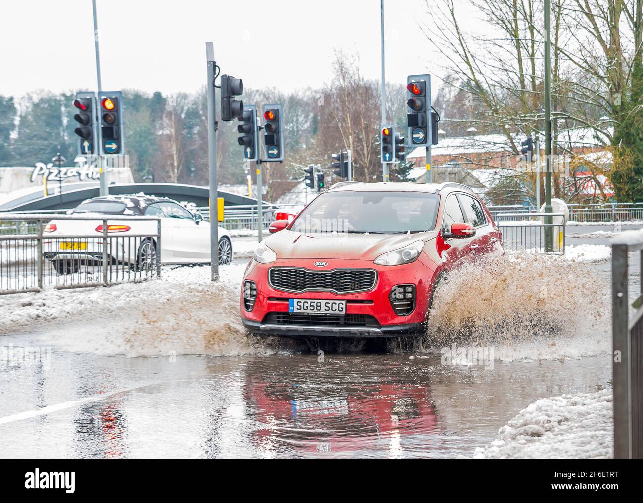 Das Auto fährt auf der Straße im Stadtzentrum und spritzt durch große Pfützen, da schmelzender Schnee Hochwasser-Probleme für den Verkehr verursacht, Kidderminster, Großbritannien. Stockfoto