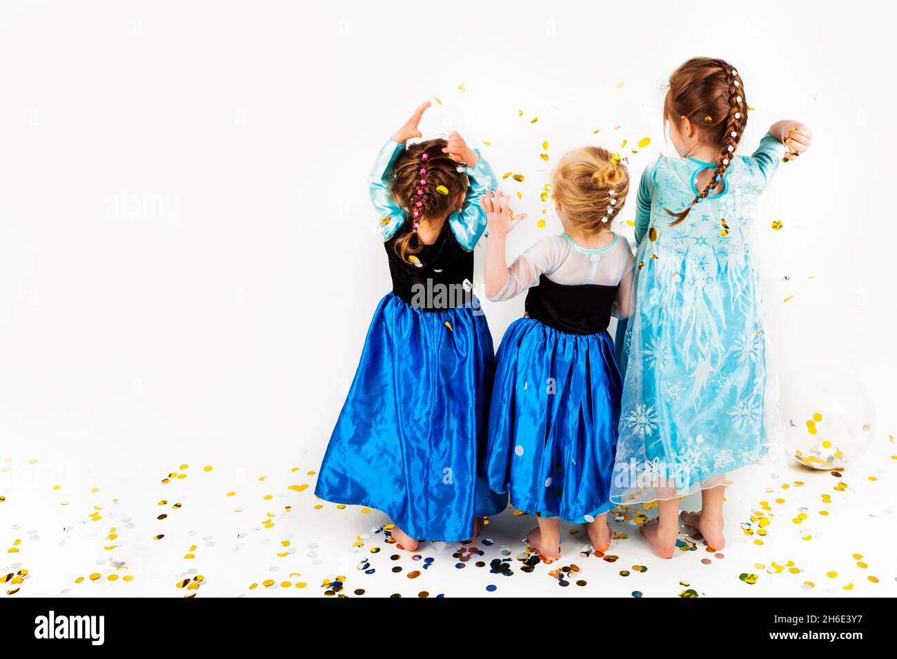 Mädchen verkleidet in ausgefallenen Kleid, bei einem Studio-Shooting, werfen Konfetti. Die Mädchenhaare sind alle geflochten, mit einem weißen Hintergrund. Stockfoto