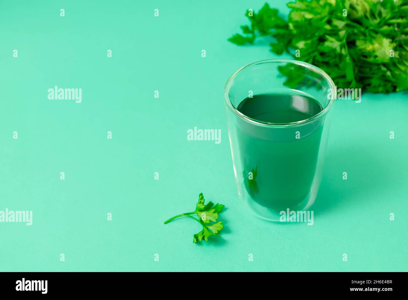 Monochromes grünes Bild mit Chlorophyllwasser in einem Glas auf grünem Hintergrund mit Platz für Text Stockfoto