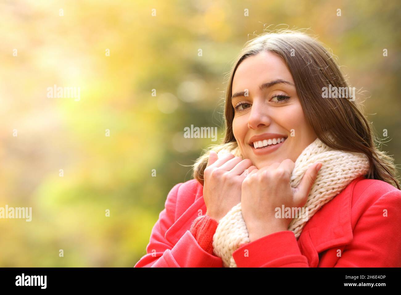 Glückliche Frau in Rot hält Wärme Blick auf Kamera im Herbst in einem Park Stockfoto