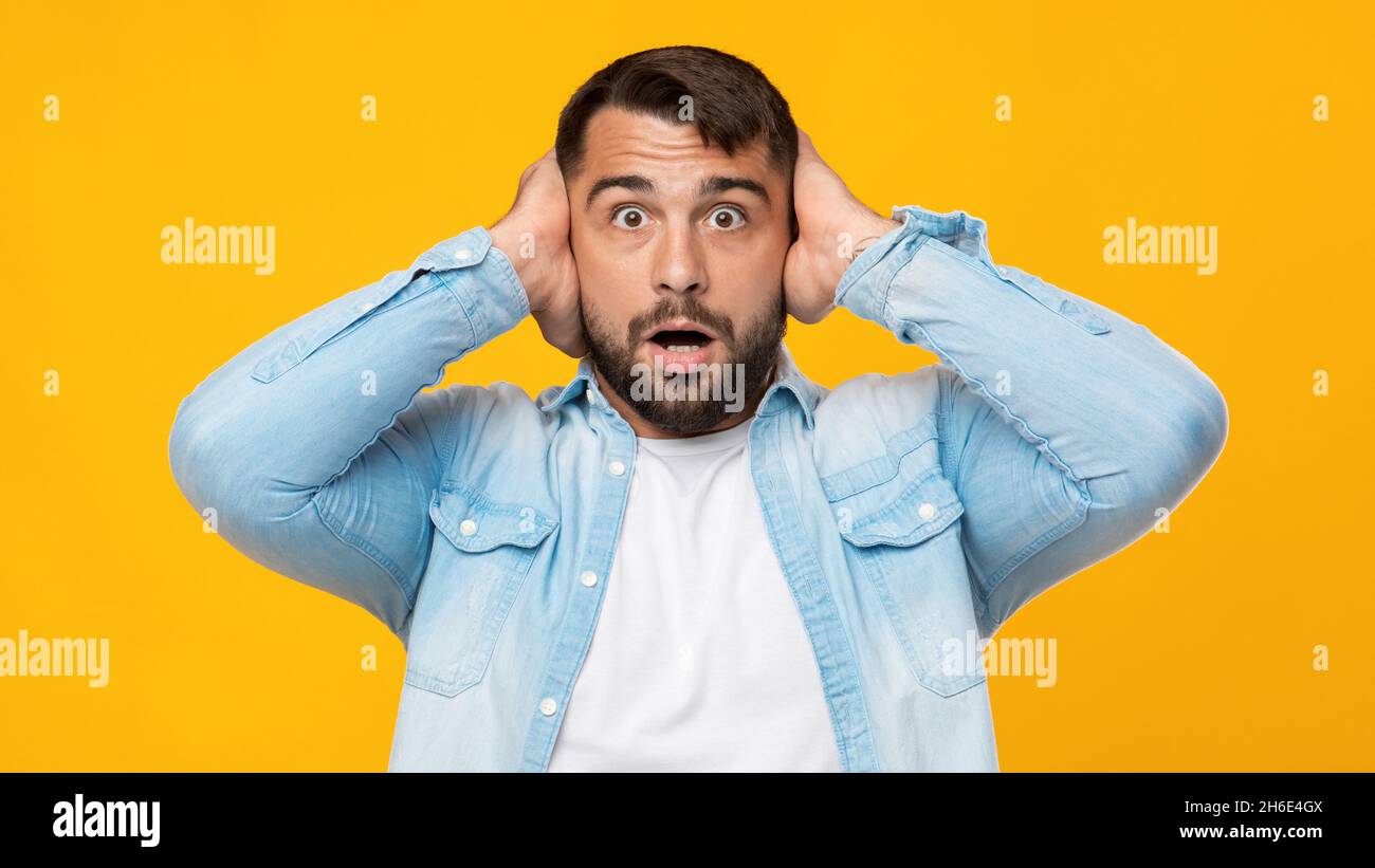 Schockiert verärgert mittleren Alters kaukasischen Kerl mit Bart bedeckt seine Ohren und will nicht hören Stockfoto