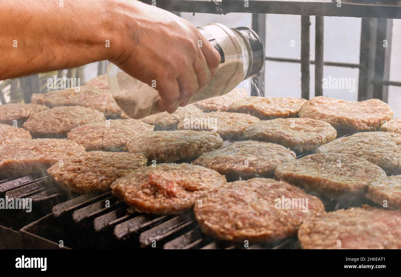 Ein handgewürzter Burger Fleisch auf einem Grill Stockfoto