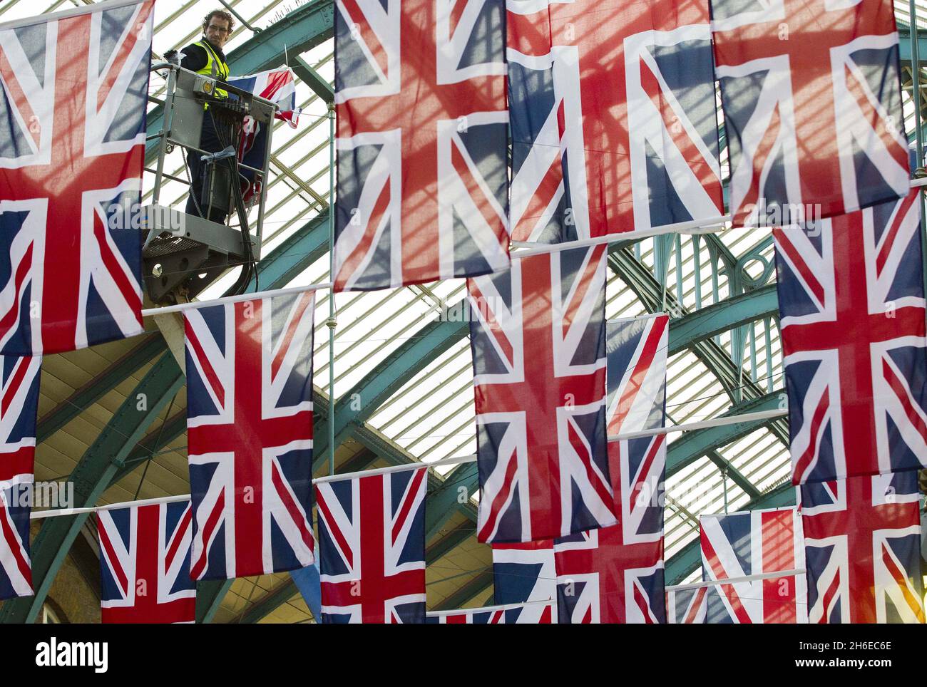 Die Arbeiter verleihen einer von über 400 Union Jack-Flaggen den letzten Schliff, die Covent GardenÃ•'s ikonisches Market Building anlässlich des Jubiläums der QueenÃ•schmücken werden. Covent Garden ist bereits Heimat der besten britischen Einkaufsmöglichkeiten und Restaurants und wird im Rahmen seiner Wochenendfeste die Londoner Street-Food-Champions Street Kitchen beherbergen. Stockfoto