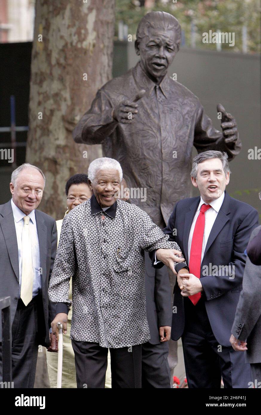 Nelson Mandela (Mitte) erhält vom britischen Premierminister Gordon Brown (rechts) eine helfende Hand, nachdem auf dem Parliament Square in London eine Bronzestatue von sich selbst enthüllt wurde, zu Ehren seines Kampfes und des vieler anderer gegen die Apartheid. Stockfoto