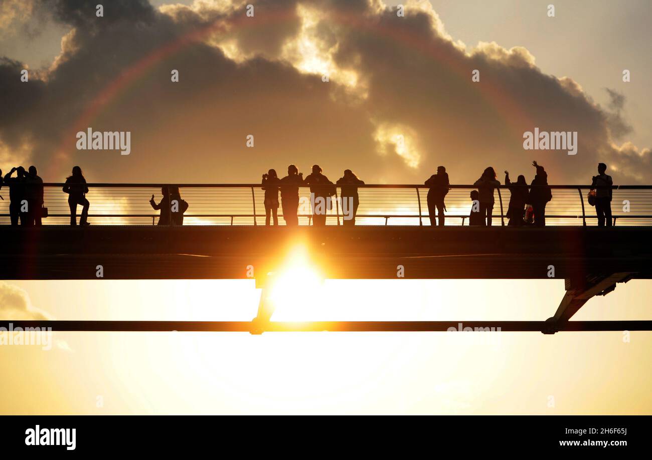 Die Millennium Bridge, die seit ihrer Eröffnung im Jahr 2000 zu einem wichtigen Teil des Londoner Lebens geworden ist. Es hat eine ganz neue Laufachse mit einer großartigen Aussicht auf St. Paul's eröffnet und den Londoner Schwerpunkt nach Süden und Osten verlagert. Es hat eine großartige Aussicht, wie diese Touristen bei Sonnenuntergang entdeckten. Stockfoto