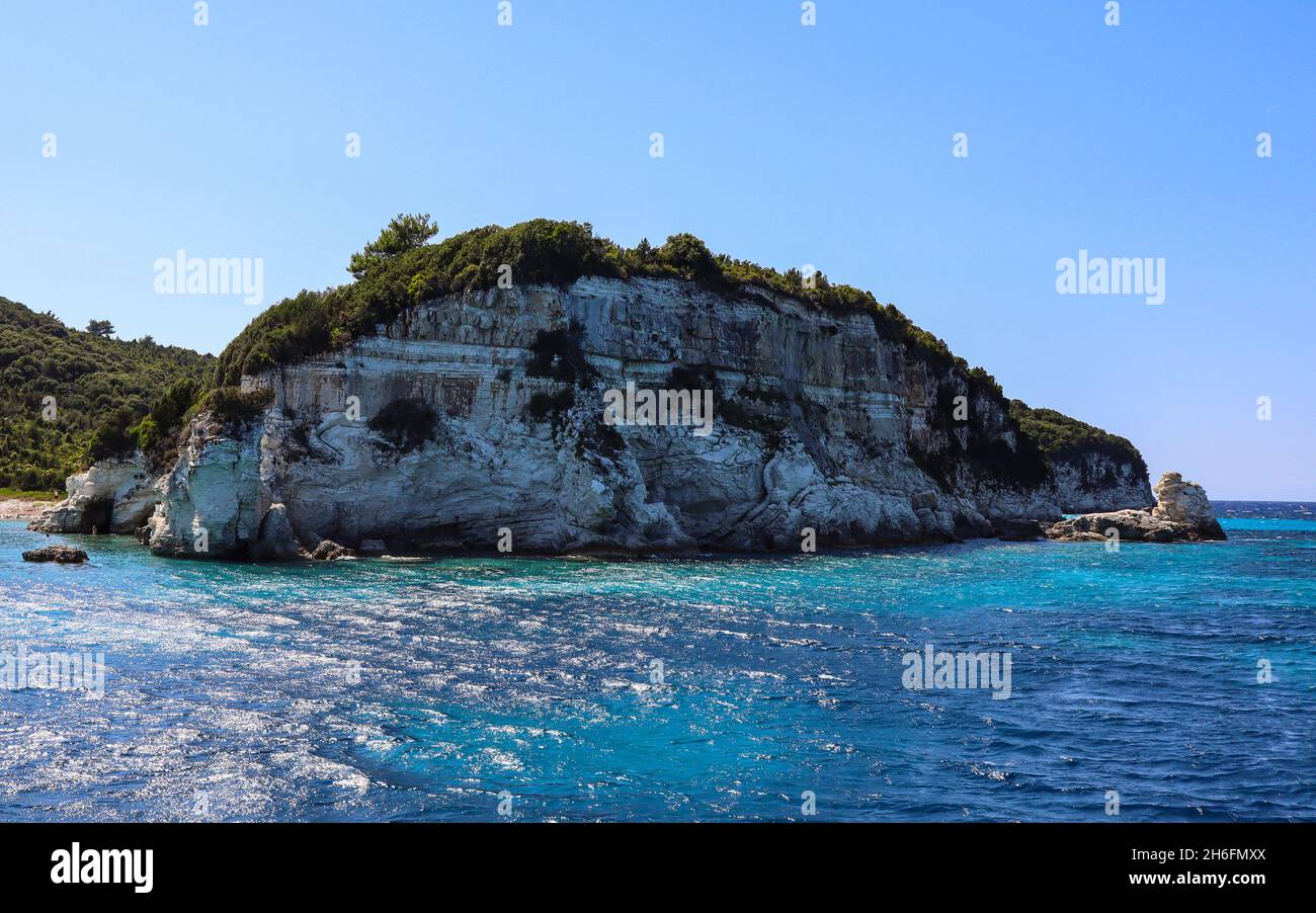 Szene von Felsklippe im Meer mit blauem Himmel und türkisfarbenem Wasser. Schöner Tag auf der Insel Antipaxos in Griechenland. Stockfoto