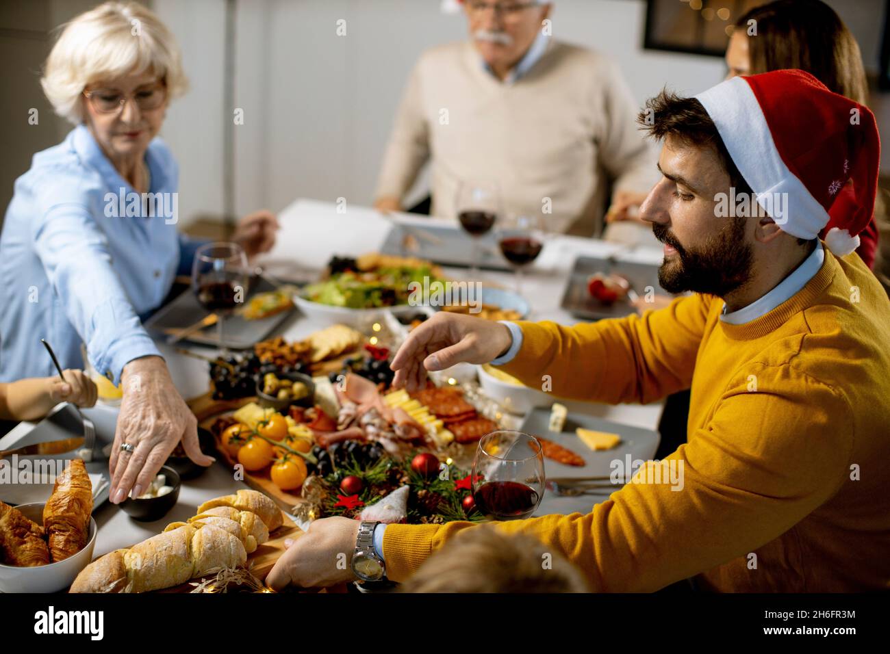 Glückliche Familie mit mehreren Generationen, die zu Hause das neue Jahr am Tisch feiert Stockfoto