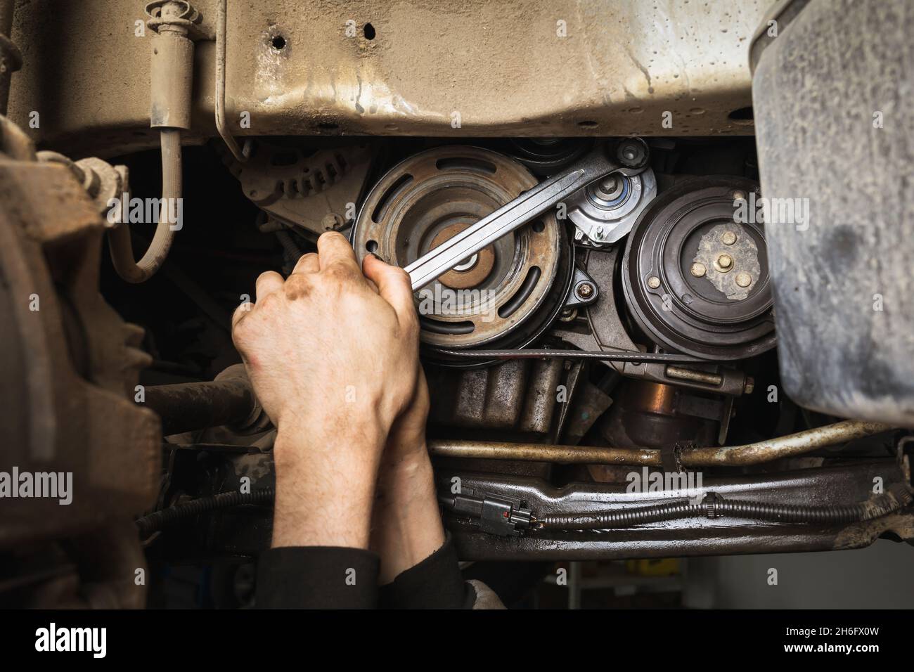 Ein Automechaniker zieht eine Schraube an der installierten neuen Motorwasserpumpe in einem Pkw an Stockfoto