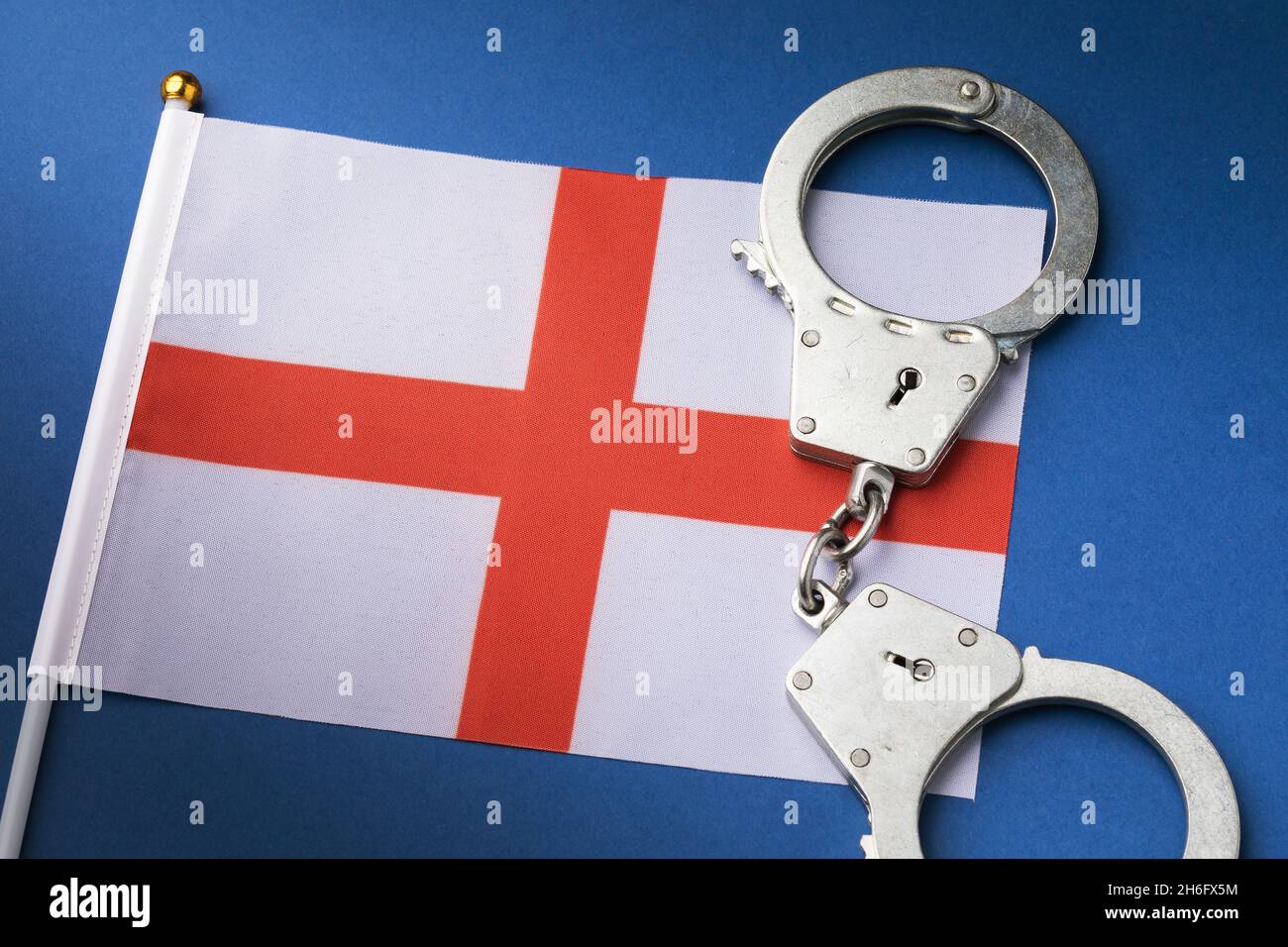 England Kreuz von St. George Rote Weiße Flagge und Handschellen auf blauem Hintergrund, Krimikonzept Stockfoto