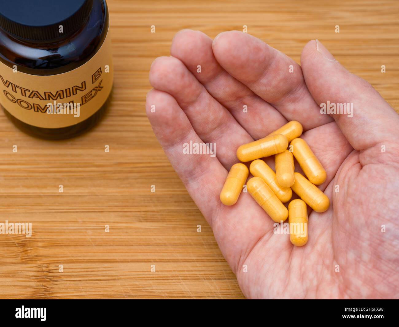 Ein Mann, der Vitamin-B-komplexe Pillen in seiner Handfläche hält. Nahaufnahme. Stockfoto