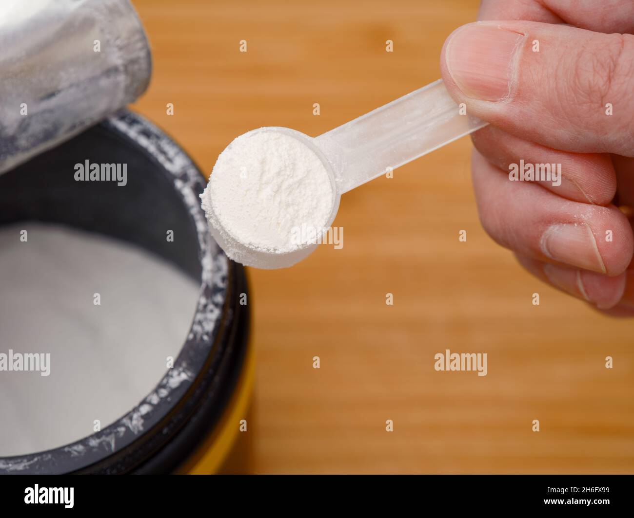 Ein Mann, der eine Messlöffel AAKG-Pulver in der Hand hält. AAKG-Ergänzung. Nahaufnahme. Stockfoto