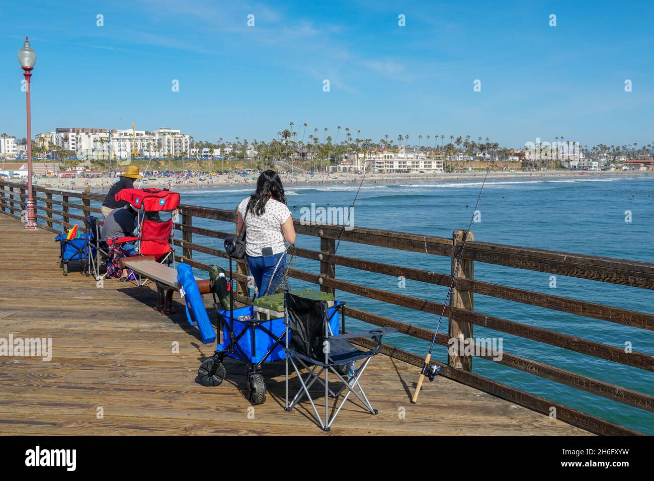 Fisher versucht während des blauen Sommertages am Oceanside Pier, Oceanside, im Norden von San Diego County, Kalifornien, Fische zu fangen. USA. November 2021 Stockfoto