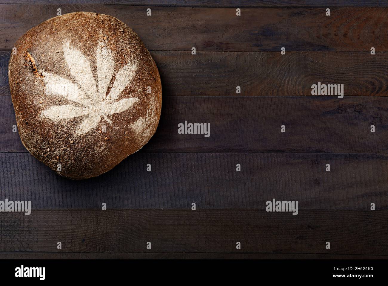 Hanfblatt-Druck auf braunem Brot, auf Holztisch-Hintergrund. Gesundes vegetarisches Essen. Stockfoto