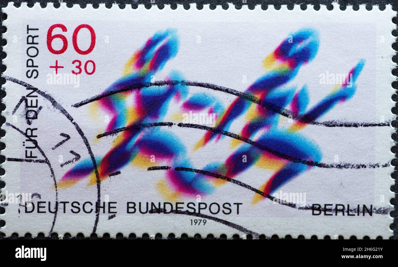 DEUTSCHLAND, Berlin - UM 1979: Eine Briefmarke aus Deutschland, Berlin zeigt zwei Staffelläufer bei der Übergabe. Text: Für Sport Stockfoto