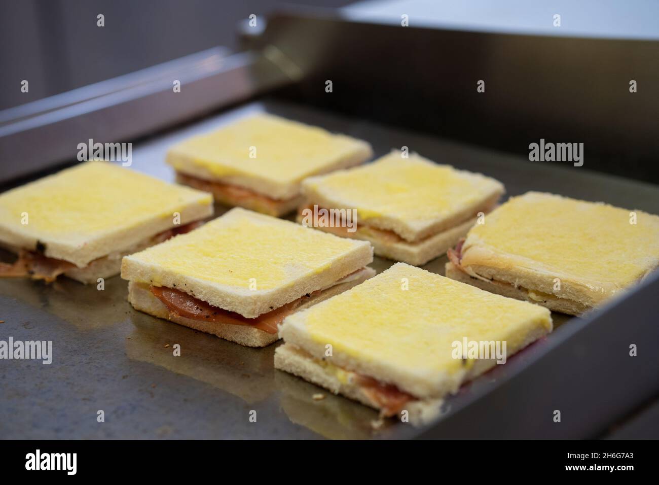 Gegrilltes und gepresstes Toast mit geräuchertem Schinken und Käse auf einem Tablett Stockfoto