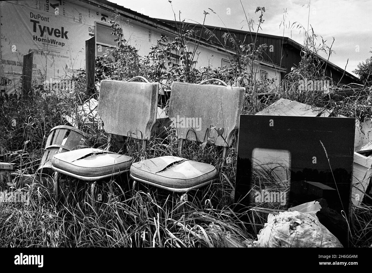 Zerrissene Stühle sitzen auf einem Haufen Müll auf dem Feld - Londonderry, NH - aufgenommen auf dem schwarz-weißen Ilford XP2-Film. Stockfoto