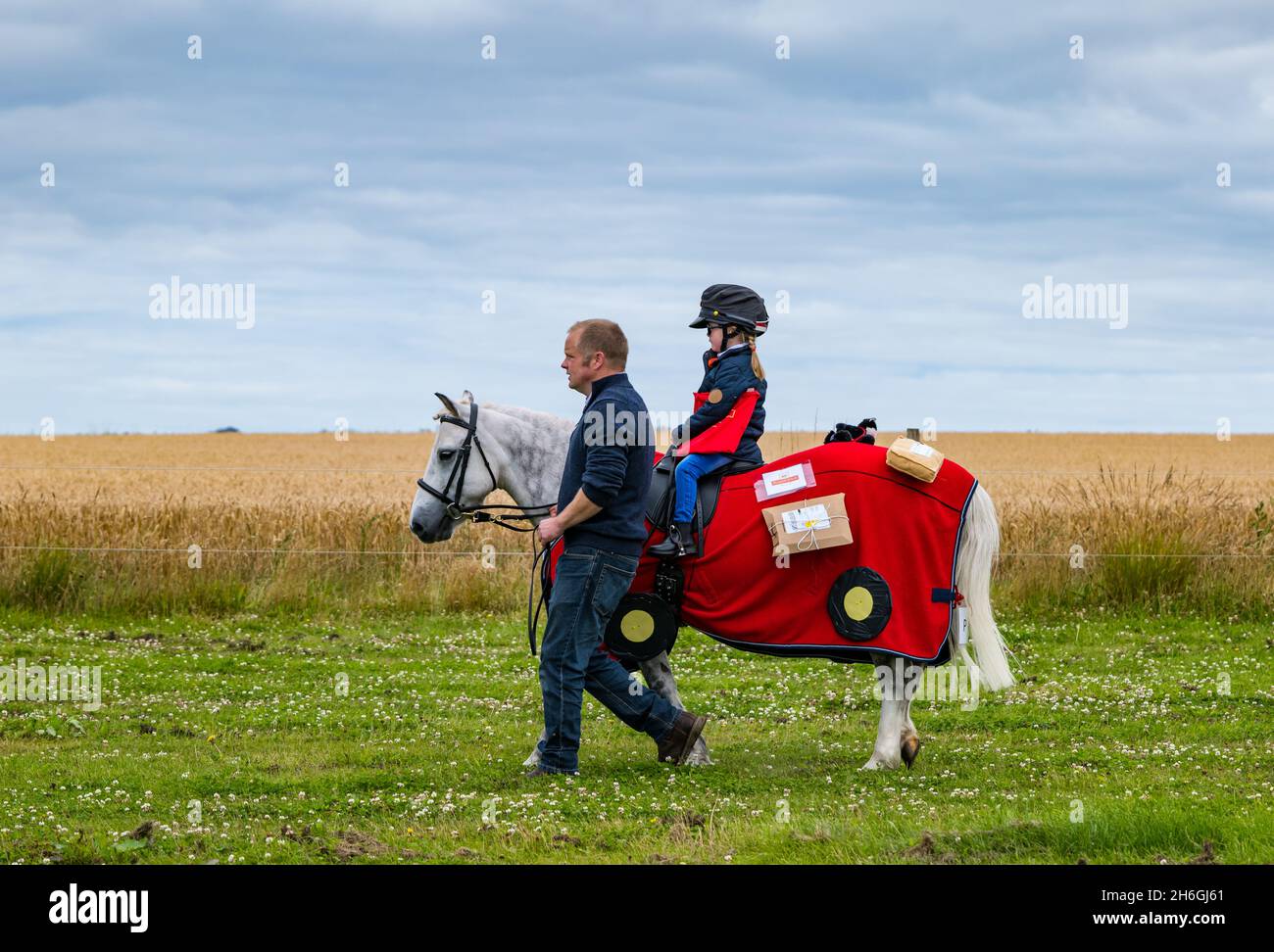 Sommerpferdeschau: Ein Kind auf einem Pony in einem Kostümwettbewerb als Postman Pat, East Lothian, Schottland, Großbritannien Stockfoto