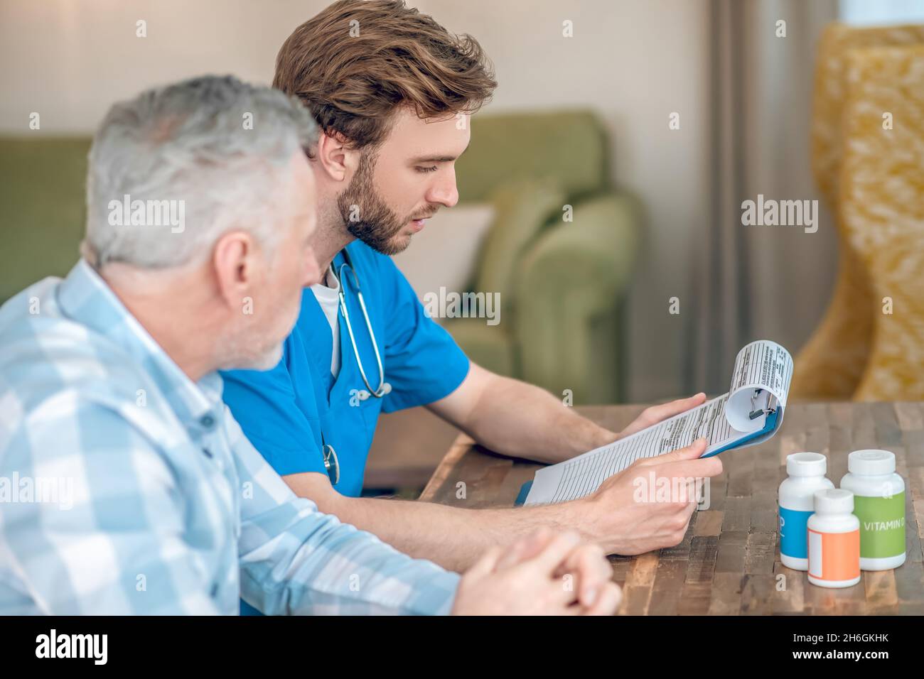 Ernsthafter Geriatriker, der einem grauhaarigen Mann Multivitamine verschreibt Stockfoto