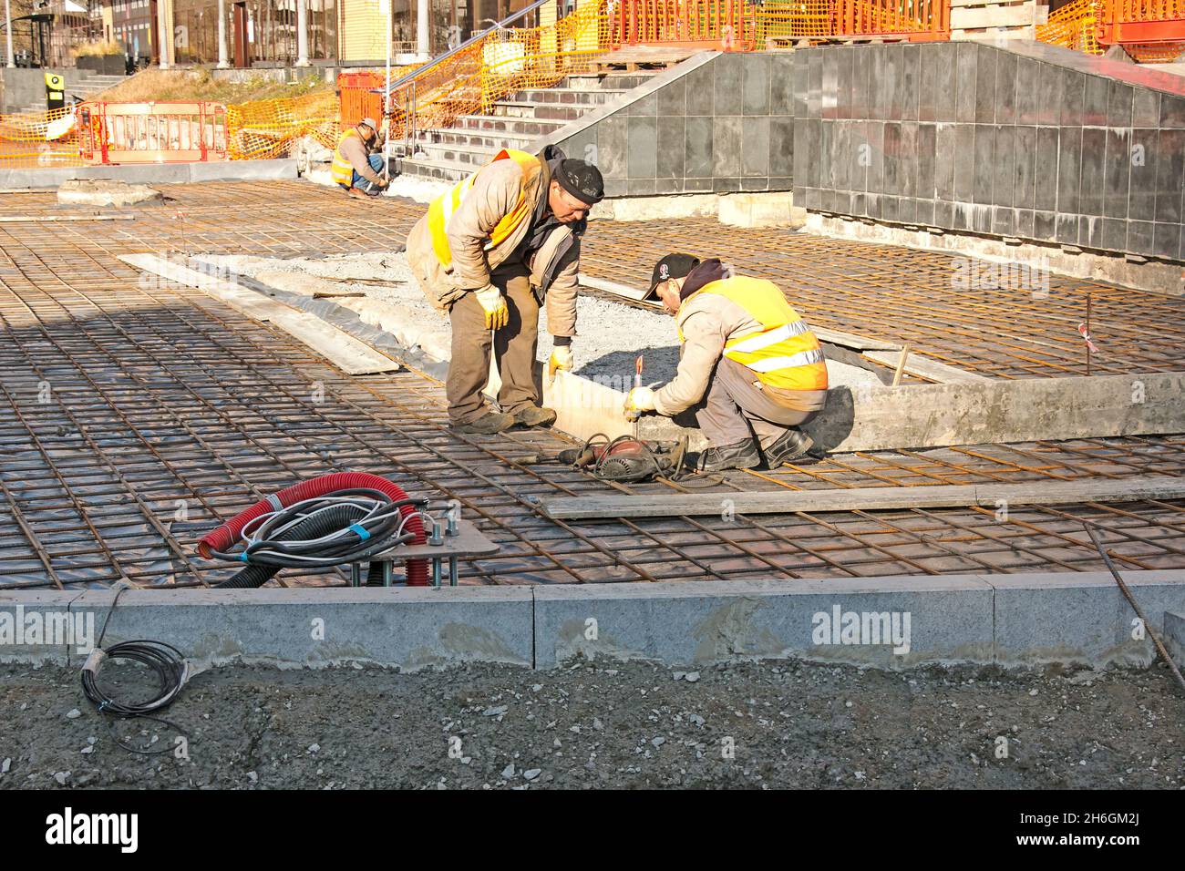 Dnepropetrovsk, Ukraine - 11.14.2021: Die Arbeiter legen ein Netz von Verstärkungen für Pflasterplatten. Die Grundlage für das Betonieren des Bürgerwegs. Stockfoto