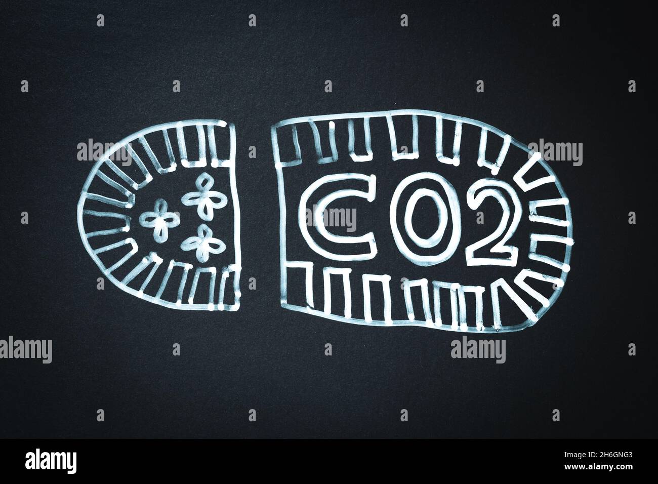 CO2-CO2-Fußabdruck – Symbol oder Konzept. Lackierter Fußabdruck auf schwarzer Memo-Tafel mit Text CO2 Stockfoto