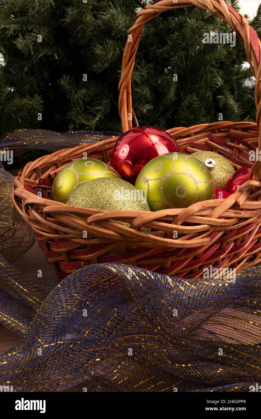 Korbkorb mit Kugeln, einige Kugeln mit Glitzer und blauem Zierband um, Dekorationen für Weihnachten im Studio, schöne Objekte Stockfoto