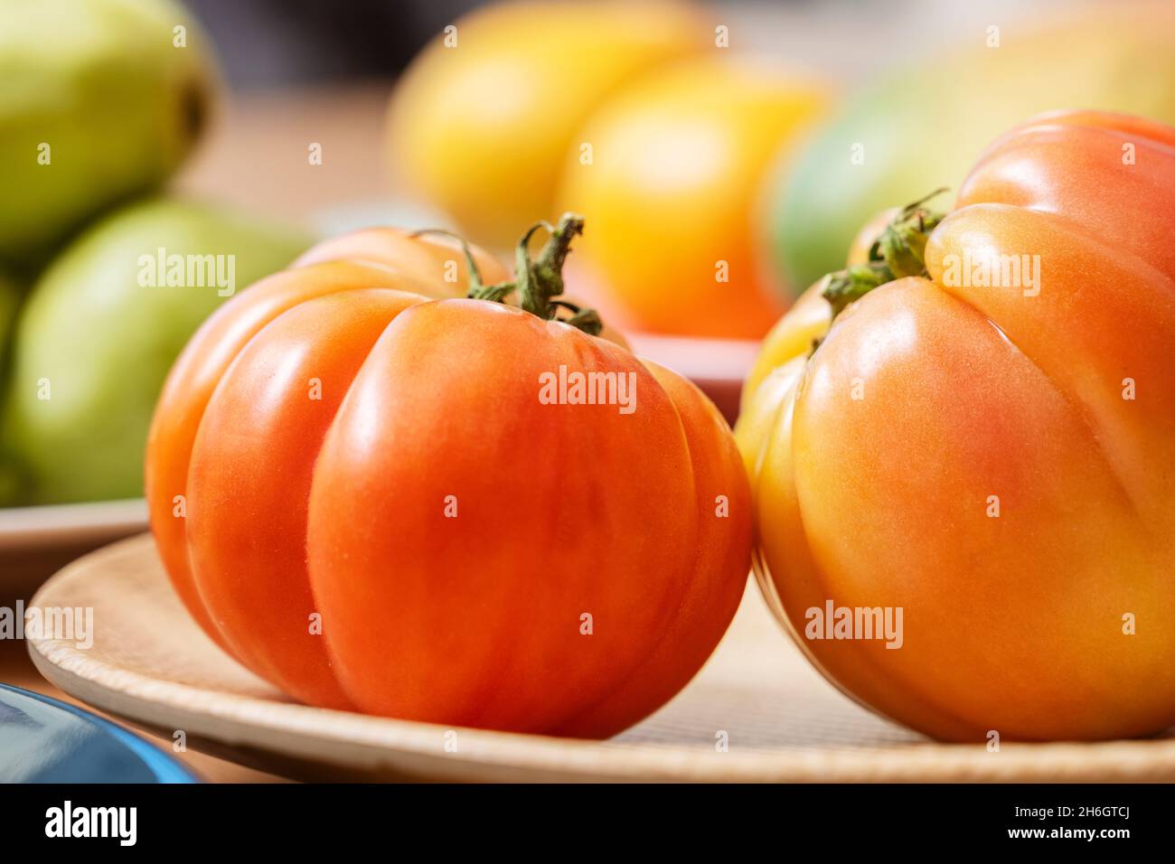 Köstliche Gerichte mit super leckeren antiken rosa Tomaten auf Holzplatte mit Struktur umgeben von anderen Früchten und Gemüse Stockfoto