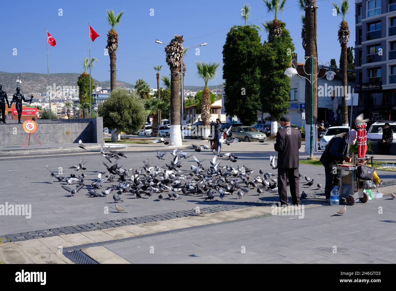 Mann, der Tauben in Kusadasi, Türkei, füttert, nachdem er Vogelfutter von einem Händler gekauft hat Stockfoto
