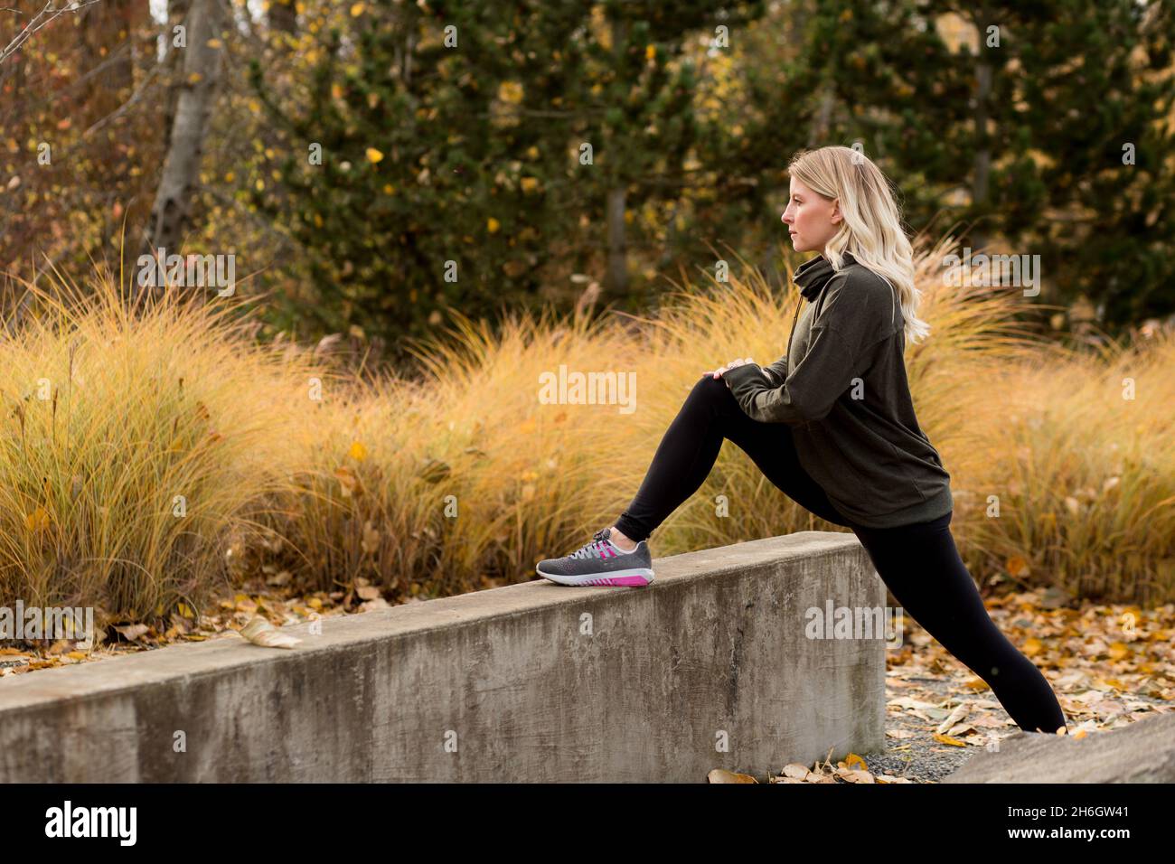 Attraktive Damen im Herbst Trainingsausrüstung dehnt sich für einen Lauf aus Stockfoto