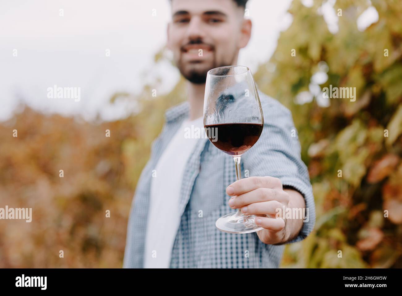 Junge zufriedene Person mit einem Glas Wein. Konzept der Weinherstellung und -Verkostung. Stockfoto