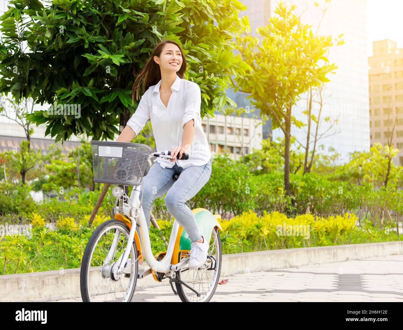 Junge attraktive Frau, die im Stadtpark Fahrrad fährt Stockfoto