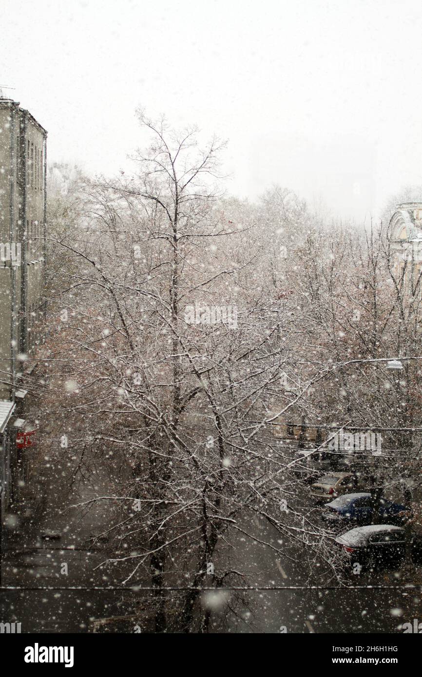 Blick auf die Straße vom Zimmer an einem trüben, bewölkten Wintertag. Der erste Schnee fällt auf die Straße. Stockfoto