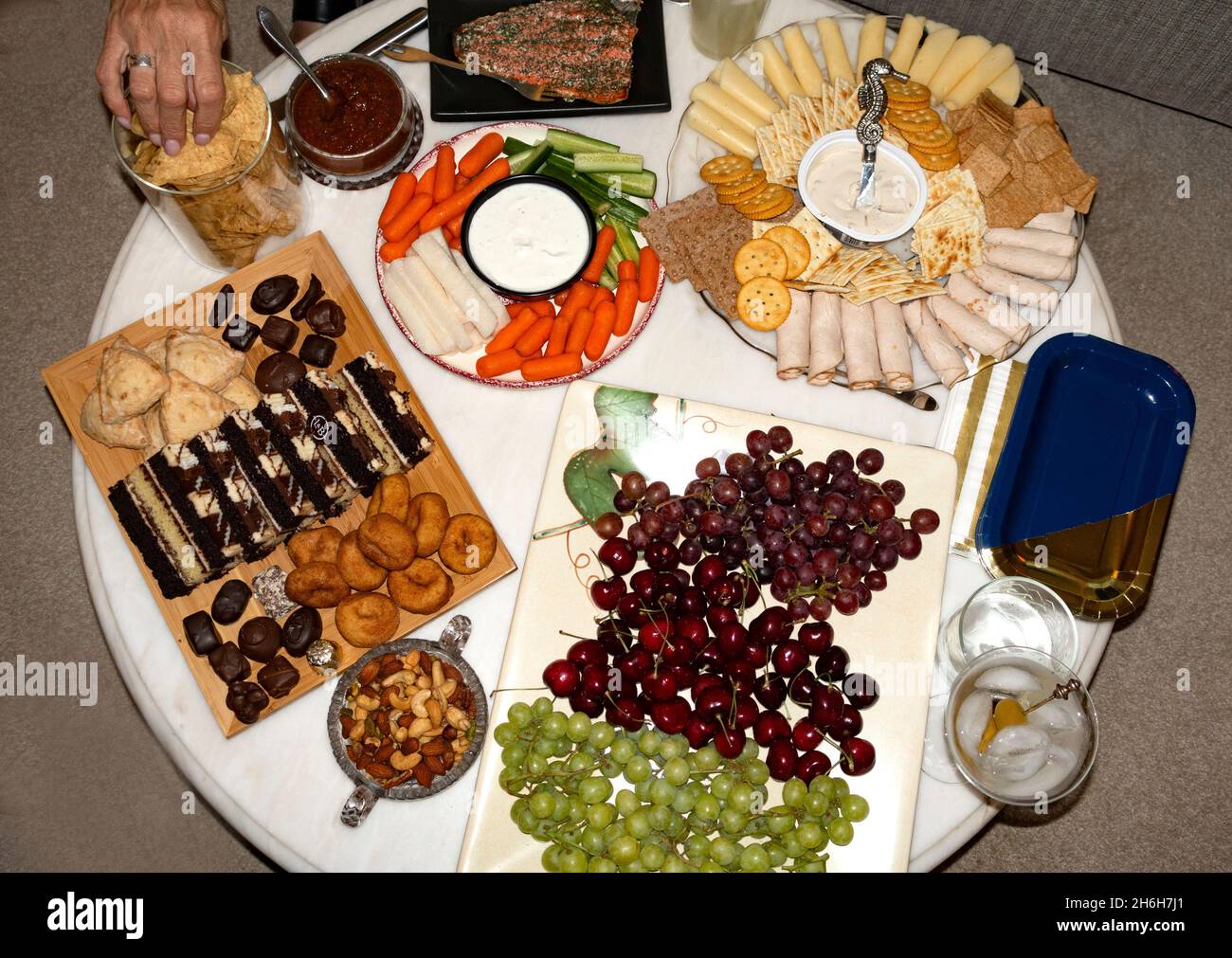 Runder Couchtisch gefüllt mit Snacks am Nachmittag, Trauben, Gemüse, Crackern, Desserts, Käse und Fleisch. St. Paul Minnesota, USA Stockfoto