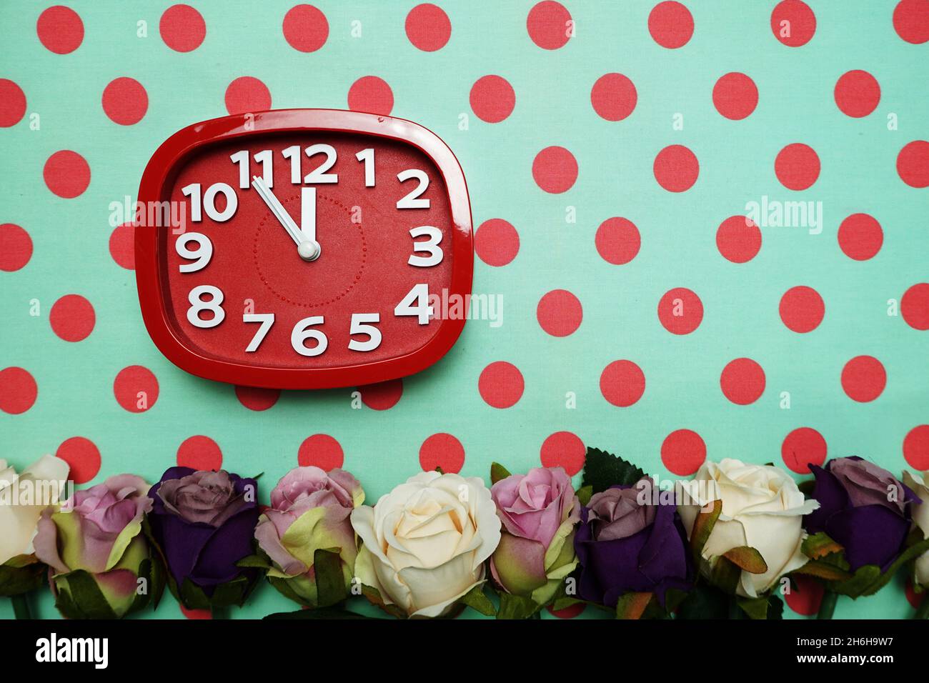 Uhr und Rosen Blumenstrauß auf grünem Polka Punkt Hintergrund Stockfoto