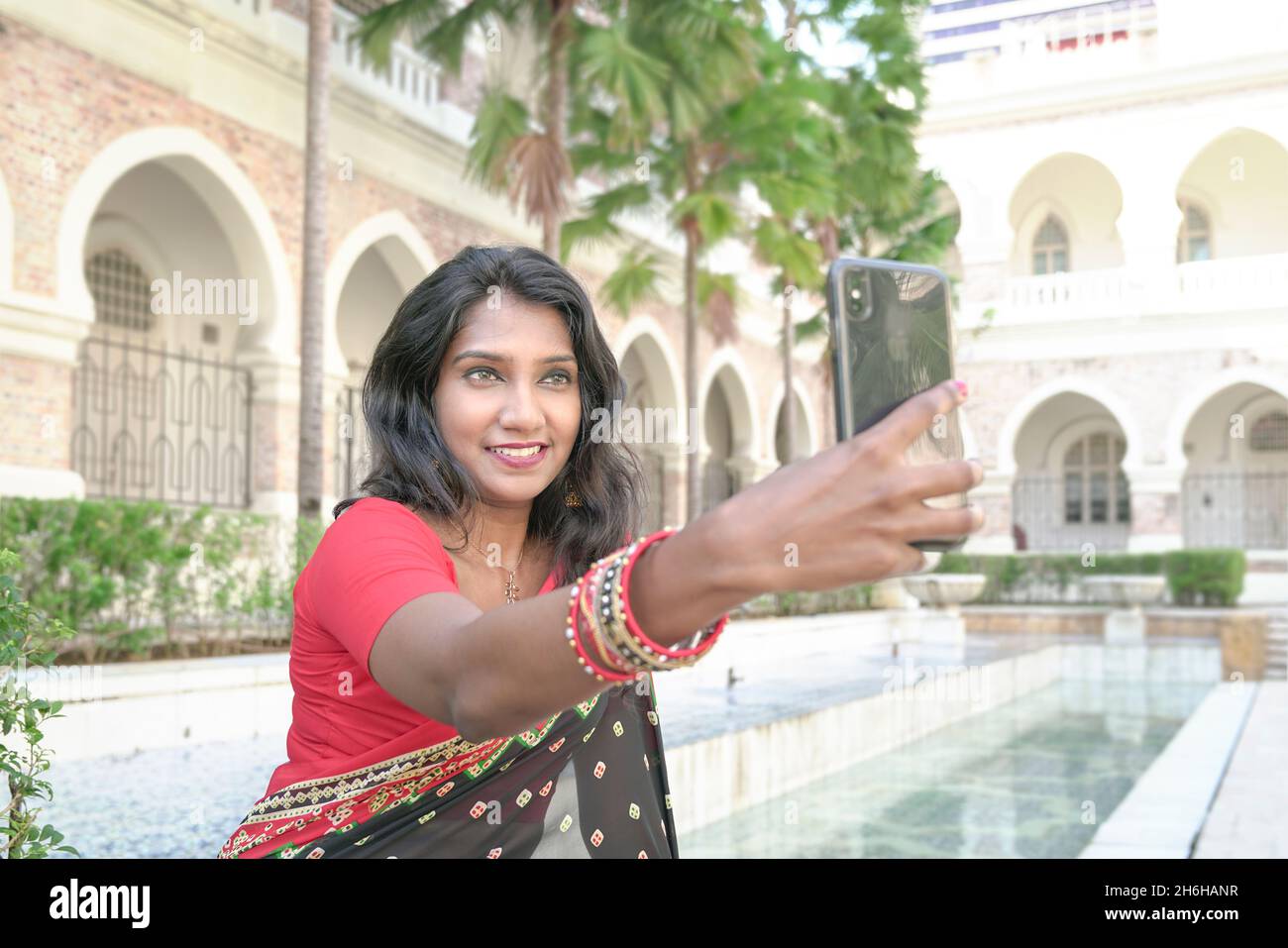 Schöne asiatische indische Frau lächelt und mit Kamera-Handy, um ein Selbstporträt zu nehmen. Stockfoto