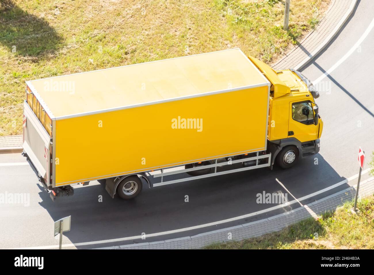 Gelber LKW mit isoliertem Container-Box dreht sich auf der Autobahn, Luftaufnahme Stockfoto
