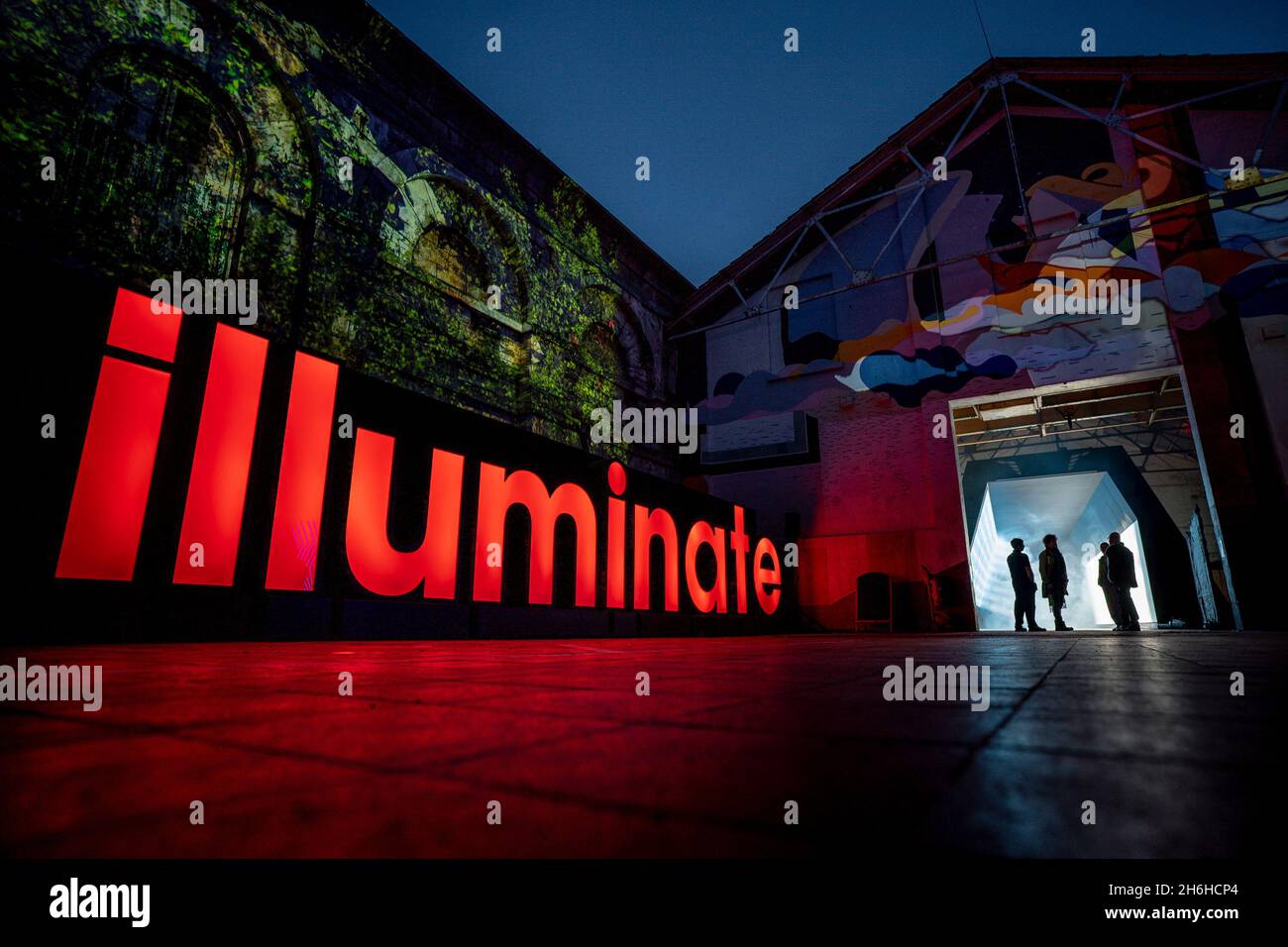 Die Menschen versammeln sich am Eingang der Kunstinstallation Sola at Illuminate, der jährlichen Lichtkunstveranstaltung im Royal William Yard in Plymouth, wo die Veranstaltung wieder eindringliche digitale Installationen präsentiert. Bilddatum: Montag, 15. November 2021. Stockfoto