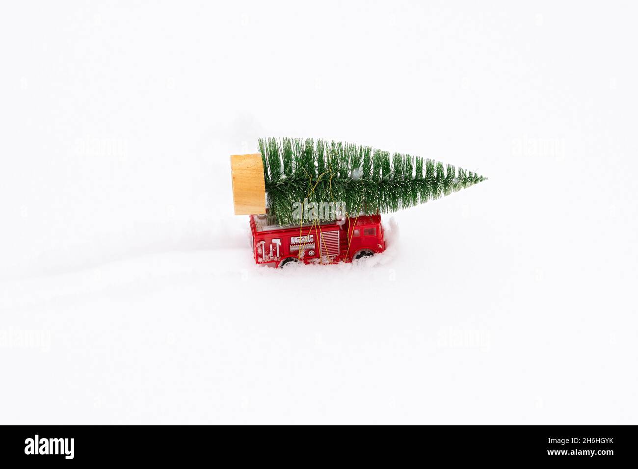 Auto Weihnachtsbaum Schnee. Lieferung von Spielzeug, Neujahrsstimmung, Geschenke auf einem roten Mini-Kinderwagen im Schnee. Das Konzept von Neujahr, Weihnachten, h Stockfoto