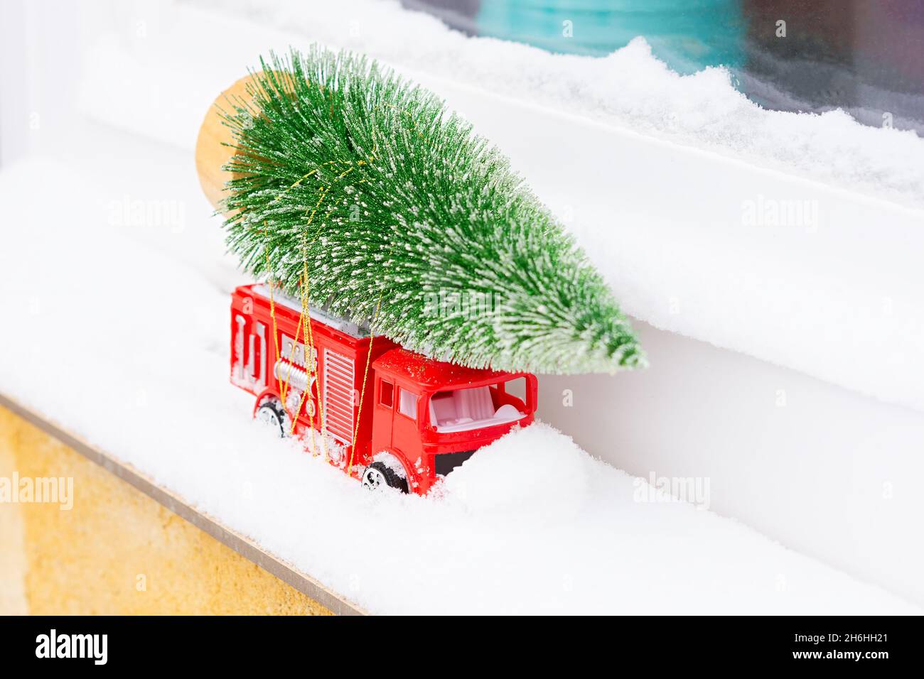 Auto Weihnachtsbaum Schnee. Lieferung von Spielzeug, Neujahrsstimmung, Geschenke auf einem roten Mini-Kinderwagen im Schnee. Das Konzept von Neujahr, Weihnachten, h Stockfoto