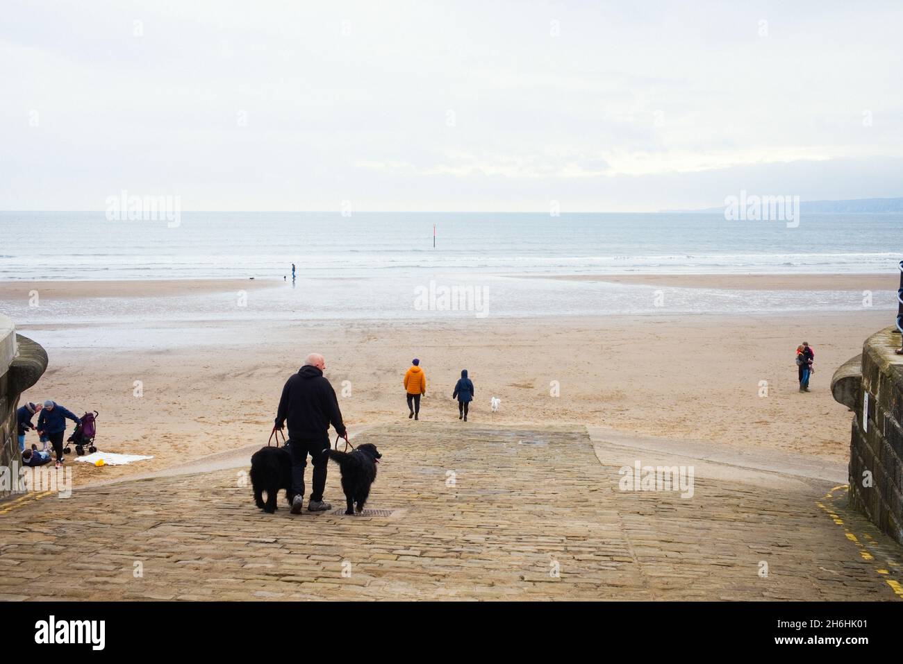 Der Slipway zum Filey Beach mit Menschen, die mit ihren Hunden spazieren Stockfoto