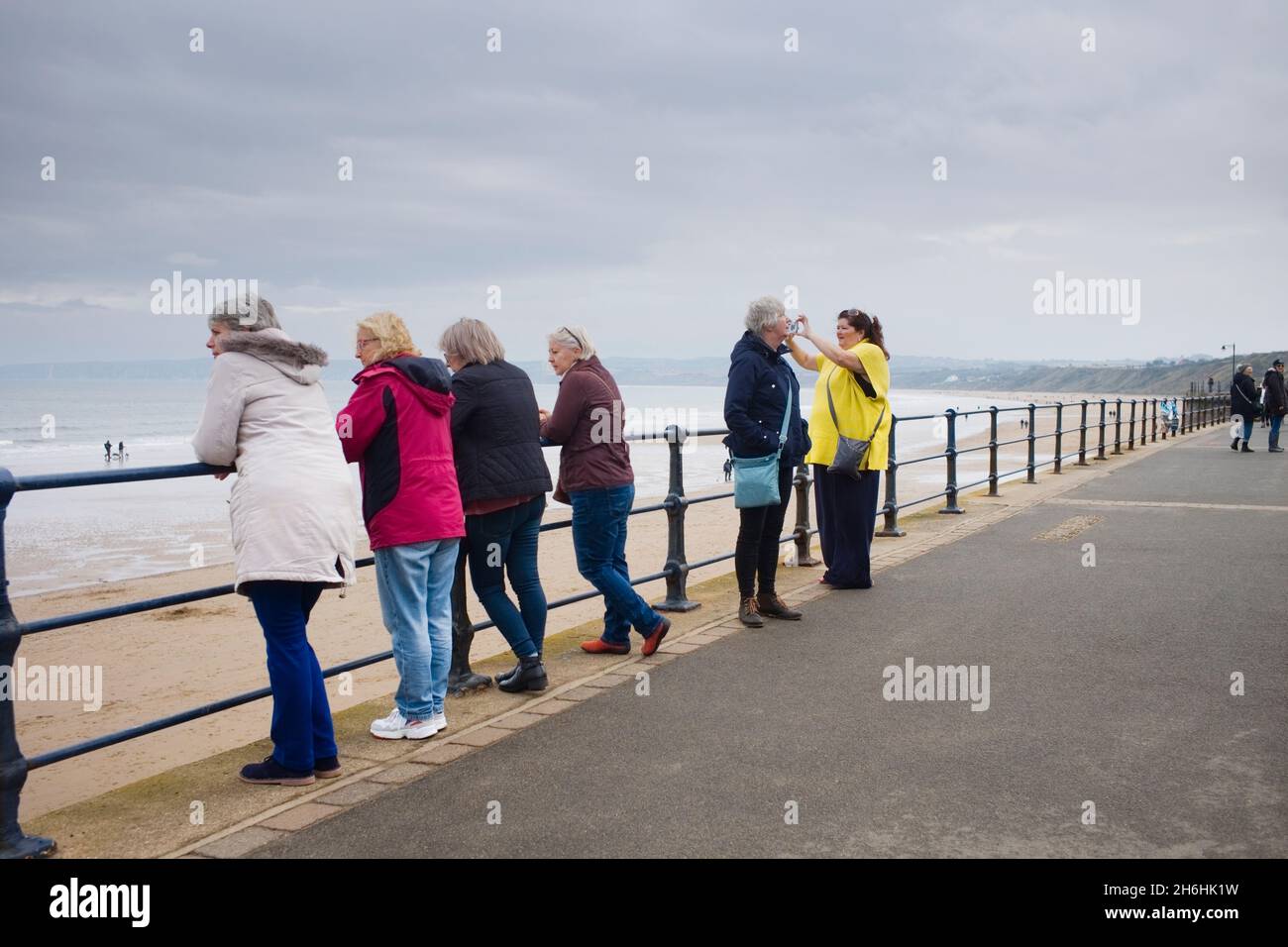 Sechs ältere Frauen und Frauen mittleren Alters blicken auf das Meer in Filey in North Yorkshire Stockfoto