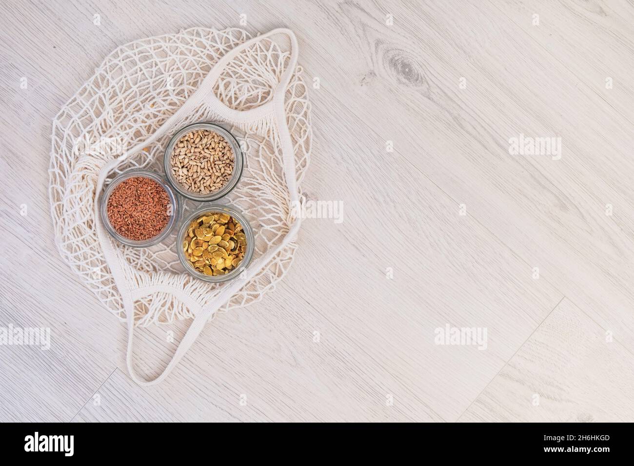 Flachs-, Sonnenblumen- und Kürbiskerne in Gläsern auf Holzboden. Bio-Saatgut in Zero Waste Shop. Verschwendearme Lebensweise. Umweltfreundliches Einkaufen in Stockfoto