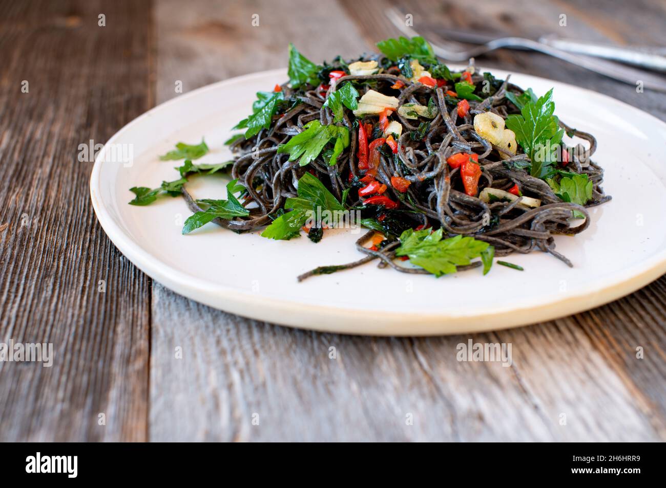 Glutenfreie und proteinreiche Linsennudeln mit Olivenöl, Knoblauch und Chili al olio. Serviert auf einem Teller mit Parley Stockfoto