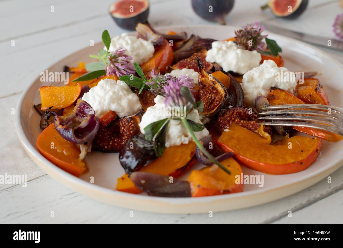 Vegetarisches Fitnessmenü mit gebratenem und karamellisiertem Pumpkin, Feigen und roten Zwiebeln, serviert mit Quark auf einem Teller Stockfoto