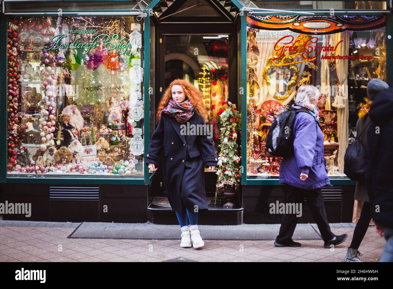 BUDAPEST, UNGARN - 08. NOVEMBER 2019: Rothaarmädchen genießen den europäischen Weihnachtsmarkt mit Menschenmassen im Hintergrund. Verschwommenes Licht und farbige Stockfoto