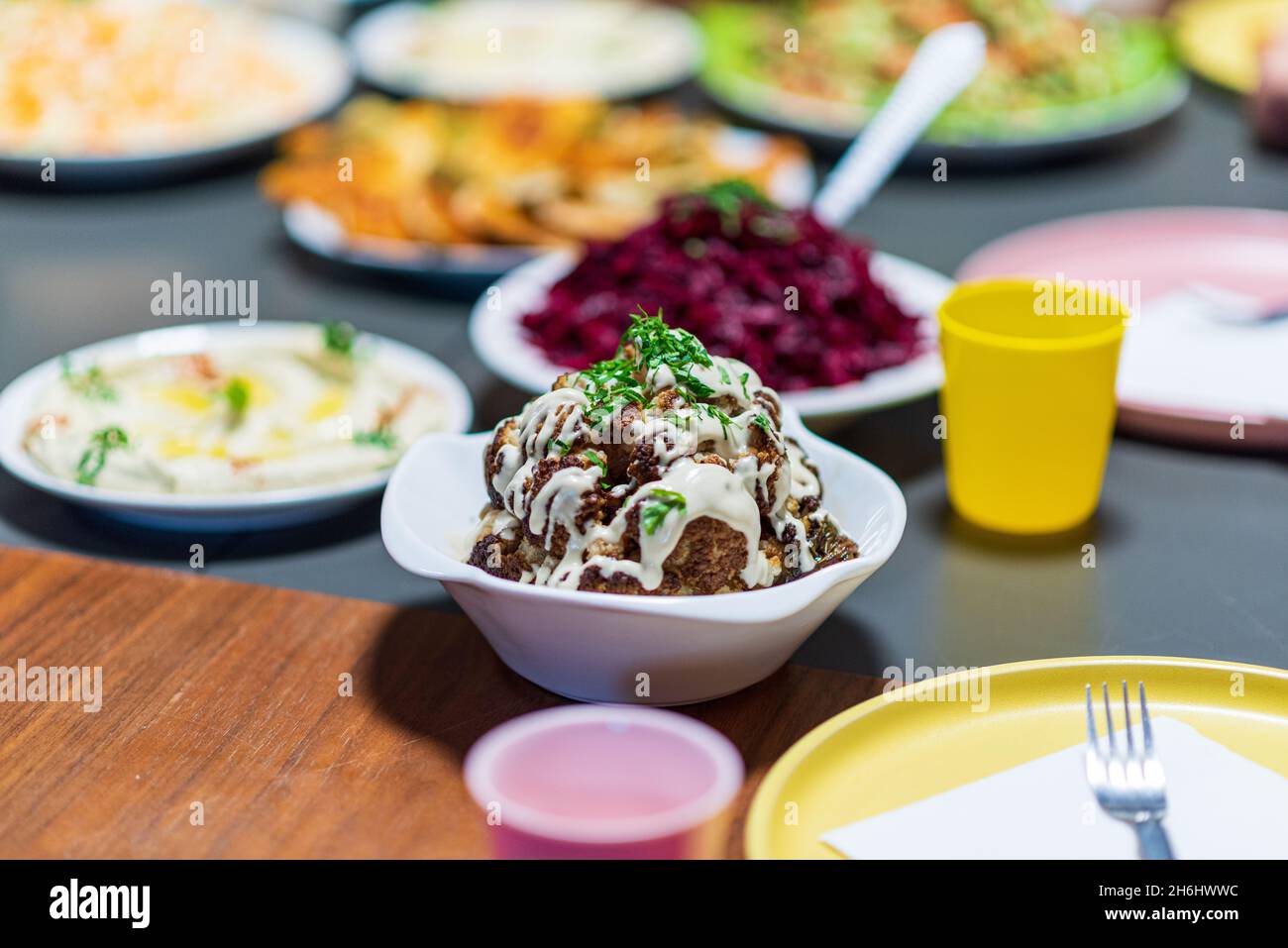 Ein ganzer Kopf gerösteten Blumenkohls mit gerösteten Zutaten und Tahini-Sauce. Nahost-Gesundheitsdiät. Mediterrane und balkanische Küche. Hochwertige Fotos Stockfoto