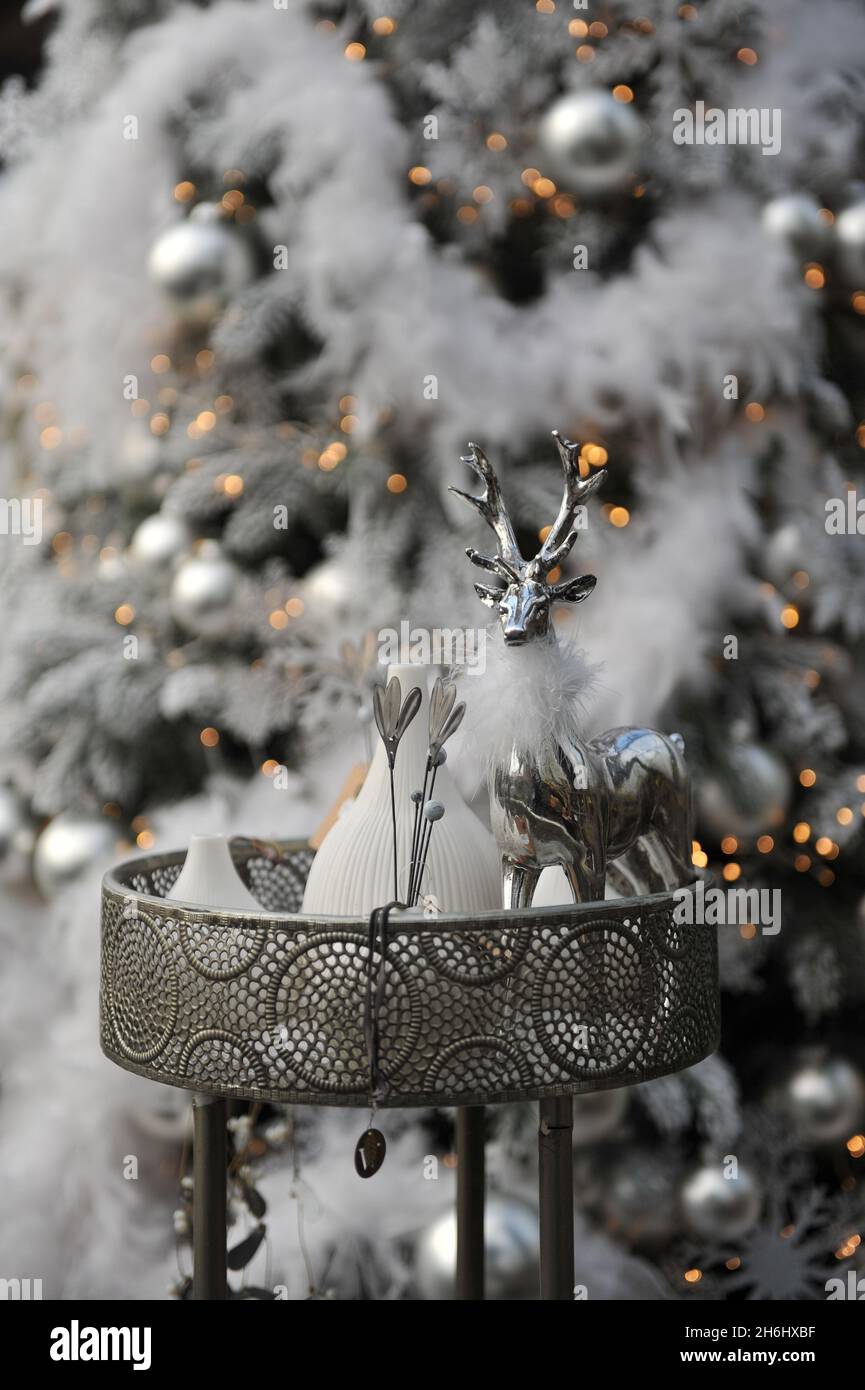 Weihnachtliche Dekoration im Innenraum. Ein silberner Hirsch und ein Weihnachtsbaum im Hintergrund Stockfoto